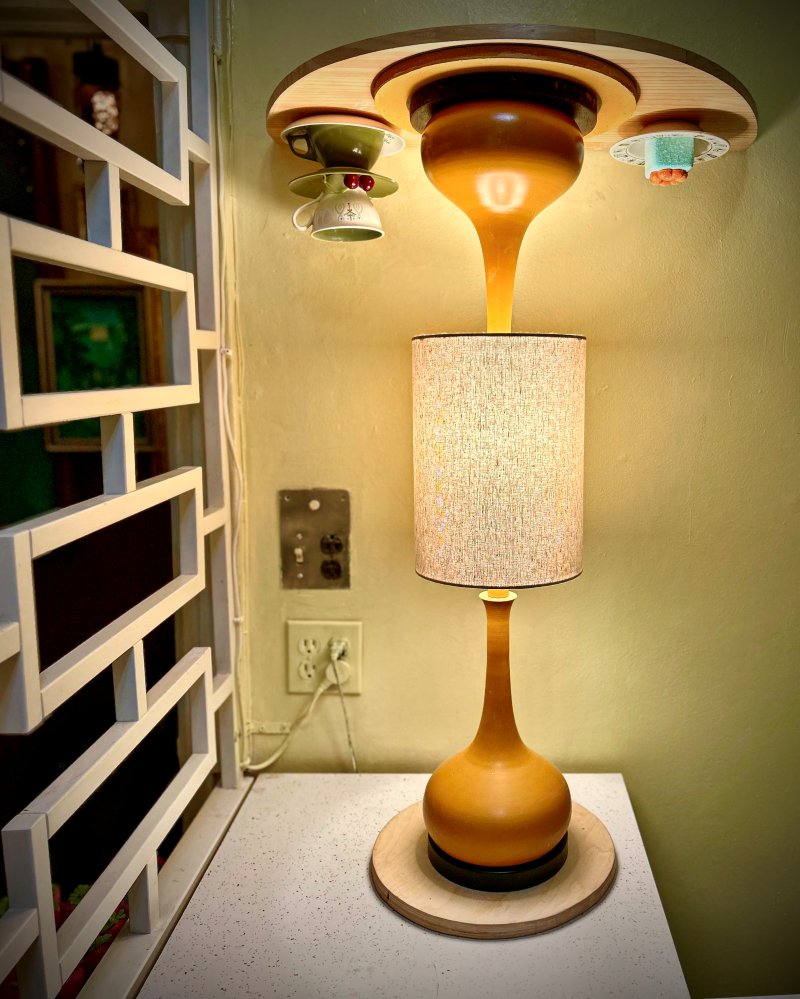 Tall mustard-yellow gourd lamp with a linen shade beside a floating teacup shelf