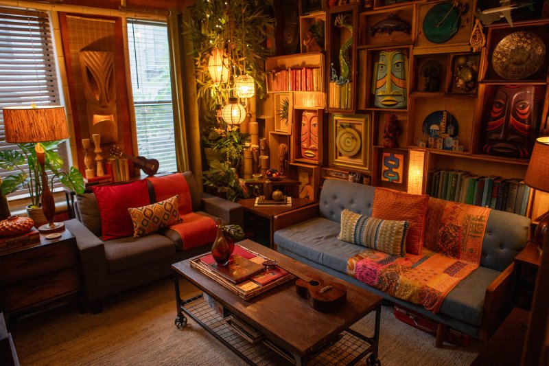 Warm tiki-style living room with a wall of carved masks above two sofas