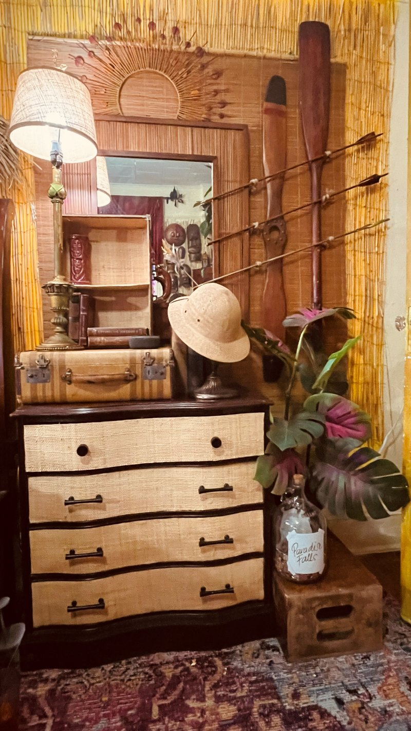 Tiki dresser vignette with a burlap-front dresser, pith helmet, and oar