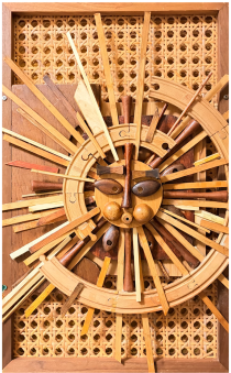 Spoke: a carved wooden face radiating dozens of dowels and curved track pieces on a woven cane panel